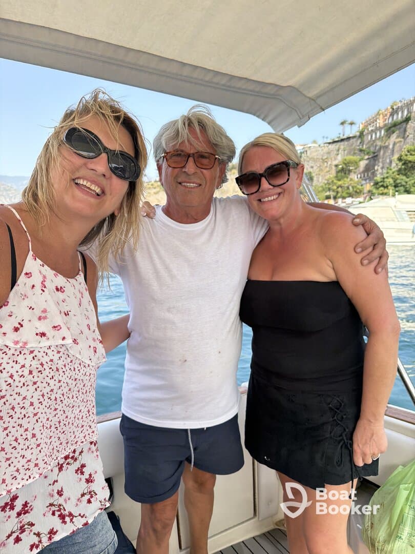A cheerful group of friends poses for a selfie on a boat, capturing a joyful moment during their maritime adventure.