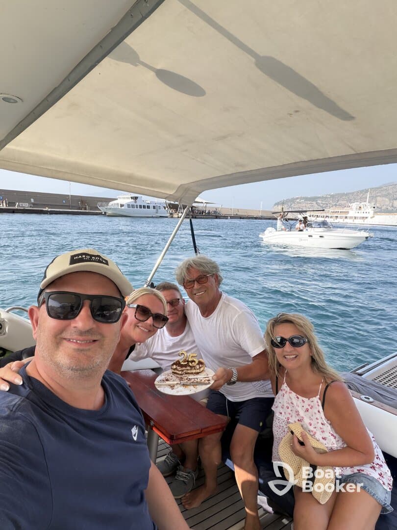 A joyful group celebrates a 25th birthday aboard a boat, complete with a delicious cake and smiles all around — perfect for memorable gatherings on the water.