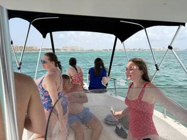 A lively group enjoys a day on the water aboard a boat, capturing moments of joy and camaraderie against a beautiful ocean backdrop.