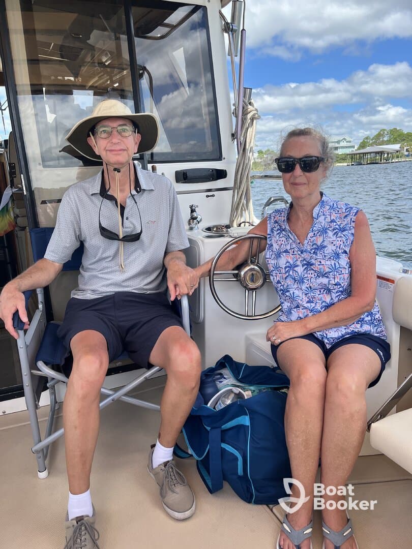 A couple relaxes inside the cabin of a boat, enjoying the view and the comfortable seating — perfect for a day on the water.