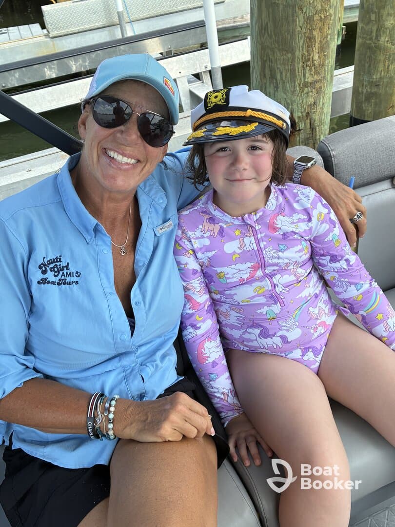 A joyful moment captured with a woman and a young girl wearing a captain's hat, enjoying their time on a boat — perfect for family adventures on the water.