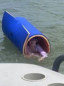 A child enjoys a playful moment in the water, peeking out from a colorful floating toy — a perfect snapshot of summer fun on the water.
