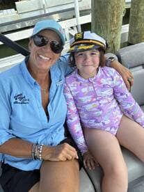 A joyful moment captured with a woman and a young girl wearing a captain's hat, enjoying their time on a boat — perfect for family adventures on the water.