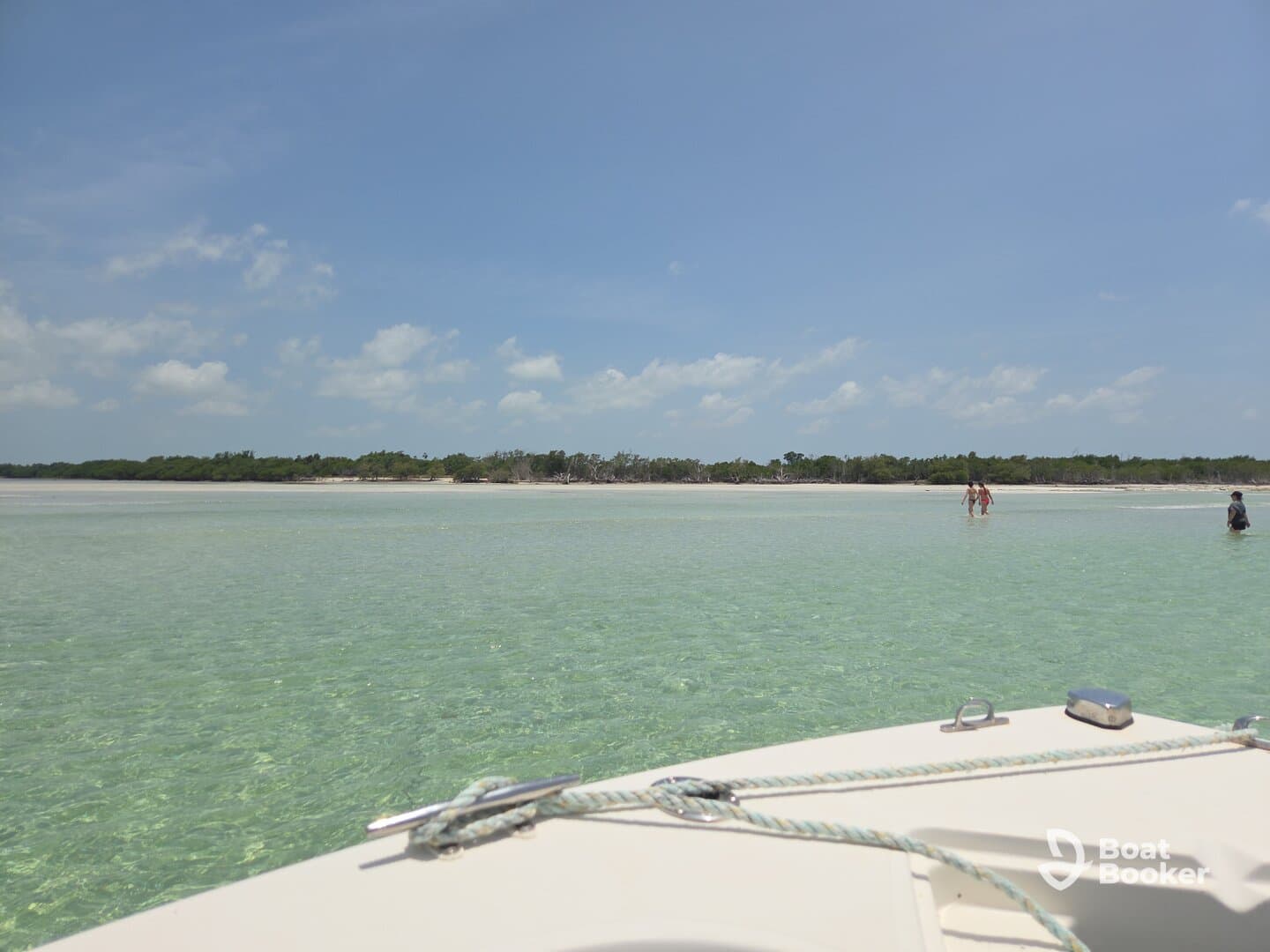 A scenic view from a boat at a sandbar, showcasing guests enjoying the shallow waters and sandy beach — a perfect spot for relaxation and fun in the sun.