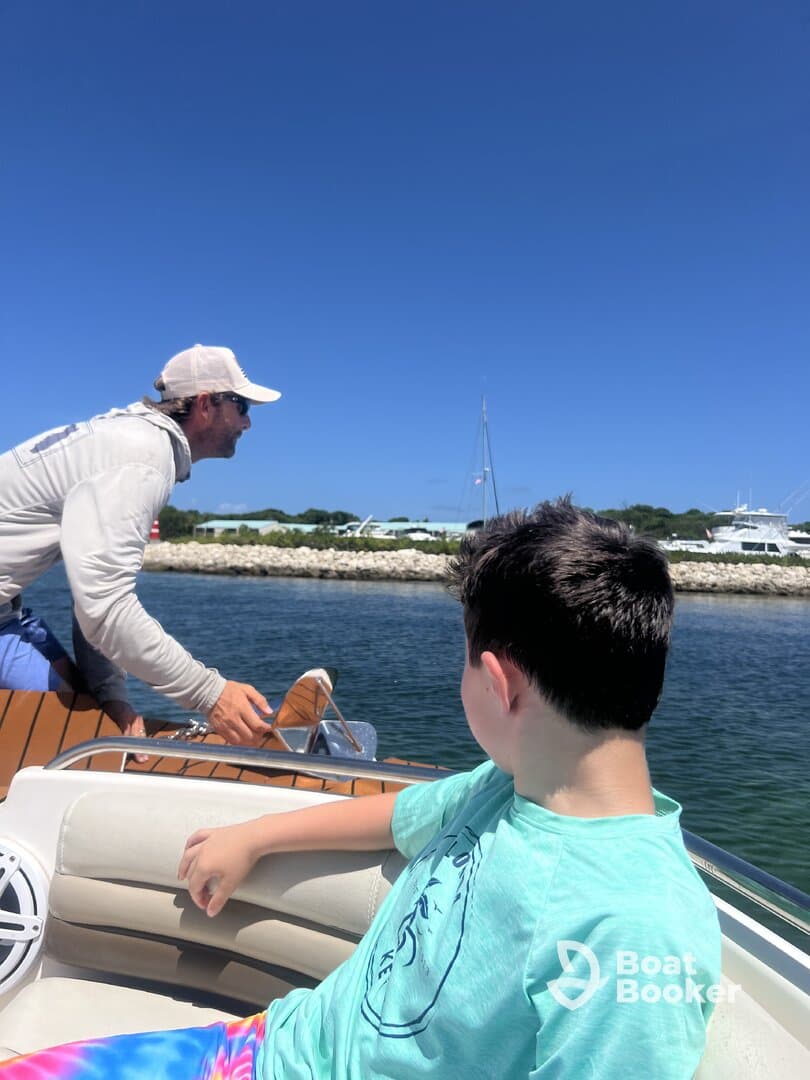 A man navigates a boat while a child looks on, capturing a moment of adventure on the water. Perfect for family outings and boating experiences.