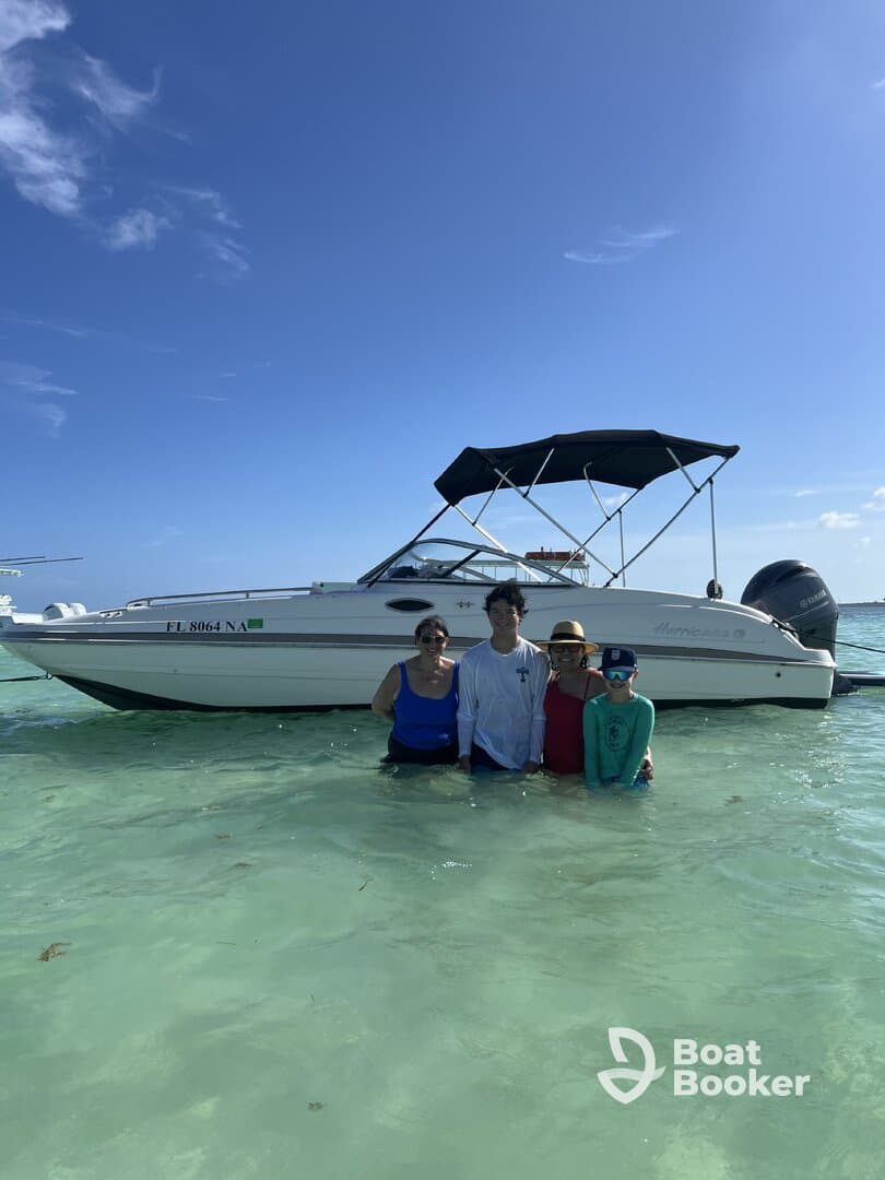 A family enjoys a fun day in the water next to their boat, creating lasting memories under the sun. Perfect for family outings and beach adventures.