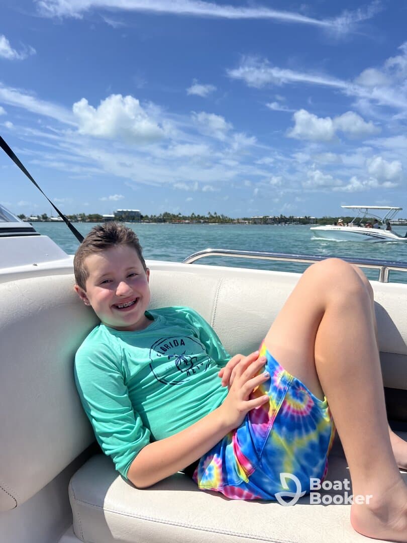 A cheerful child relaxes on a boat, enjoying a sunny day on the water — perfect for family outings and fun adventures.