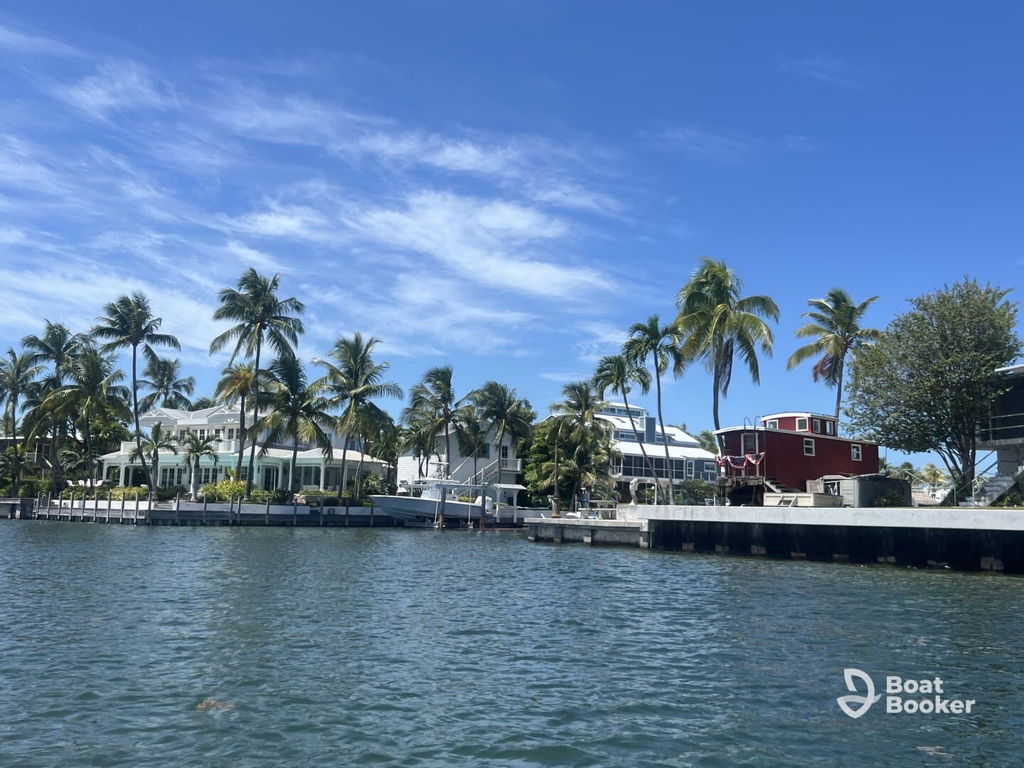 A scenic view of waterfront properties surrounded by palm trees under a clear blue sky, showcasing the beauty of tropical living.