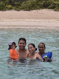 A joyful family enjoys a fun day swimming in clear waters, creating lasting memories at the beach.