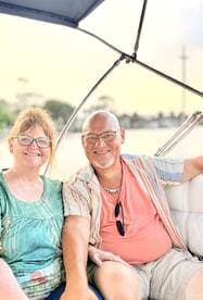 A smiling couple enjoys a relaxing moment on a boat, perfect for sunset cruises or romantic getaways on the water.