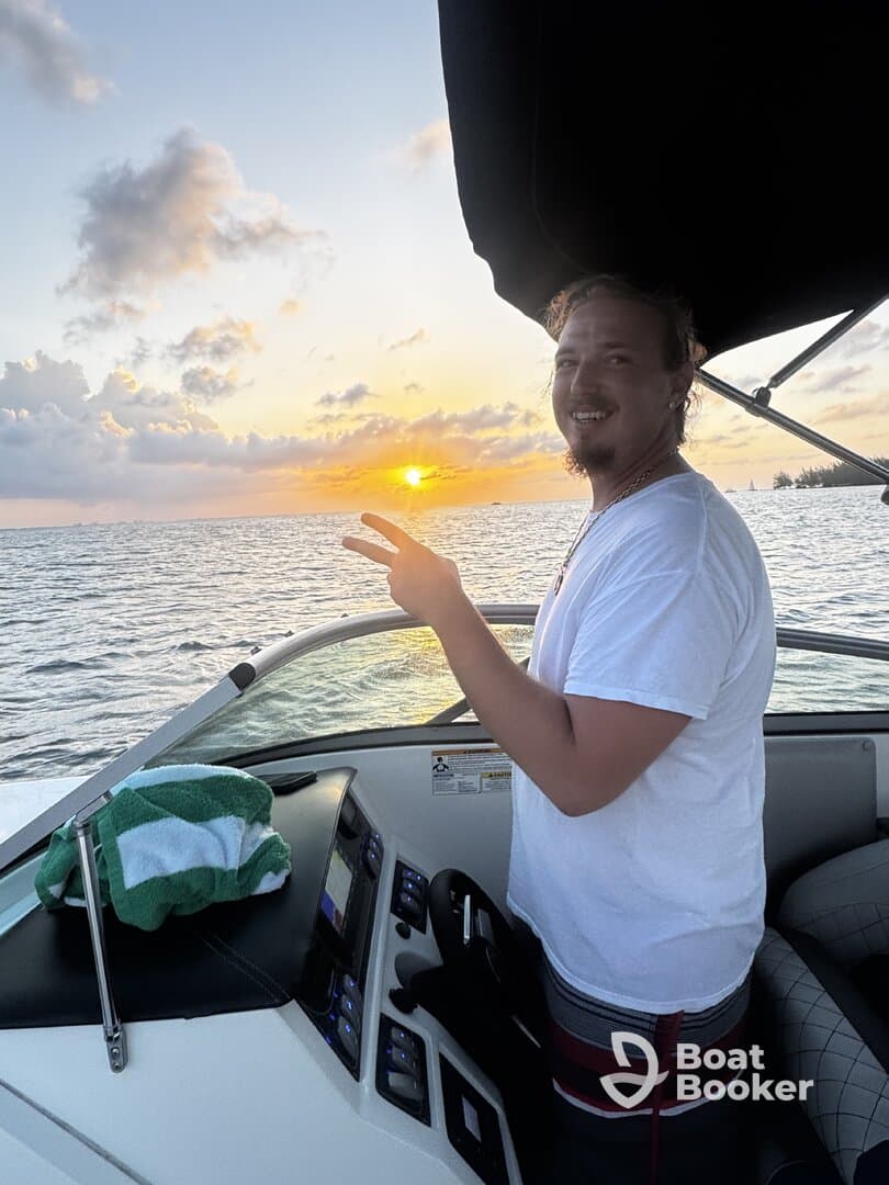 A joyful moment captured as a man enjoys a sunset on a boat, showcasing the perfect atmosphere for relaxation and celebration on the water.