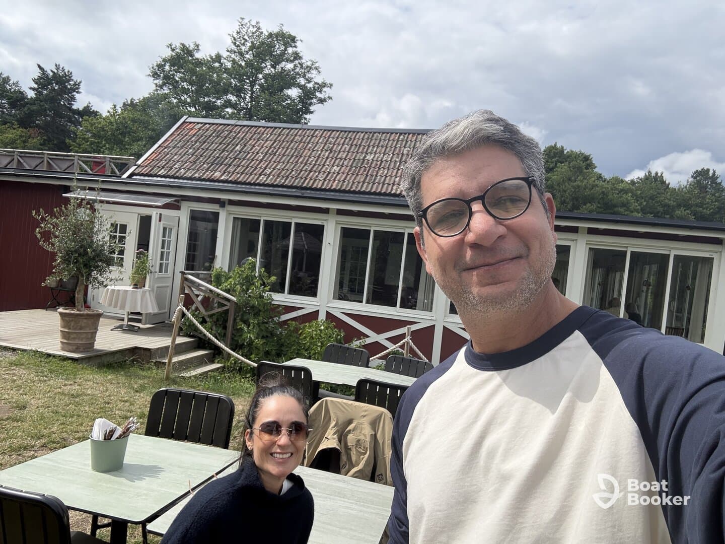 A couple poses for a selfie outside a building, capturing a casual moment in a scenic setting.
