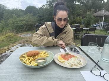 A guest enjoys a delicious meal featuring fries and seafood at an outdoor dining area, perfect for a relaxing meal after a day on the water.
