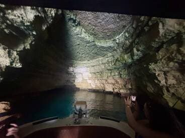 A captivating view of a cave's interior as a guest captures the moment on their phone while aboard a boat — a perfect blend of adventure and natural beauty.