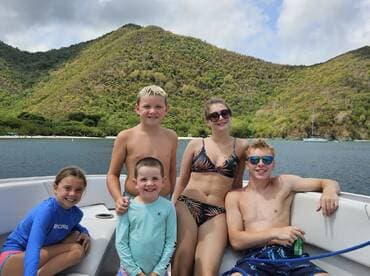A joyful group of children and teens enjoy a sunny day on a boat, surrounded by beautiful scenery — perfect for family outings and adventures on the water.