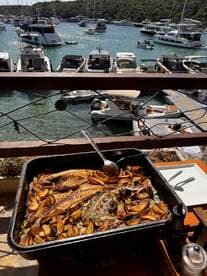 A delicious spread of grilled fish and potatoes served at a waterfront dining area, perfect for enjoying fresh seafood while overlooking the marina.
