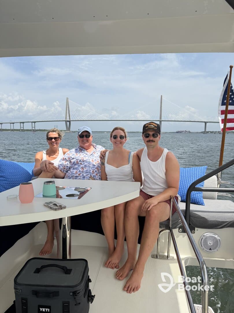 A cheerful group enjoys their time on a boat with a stunning bridge in the background, perfect for family gatherings or celebrations on the water.