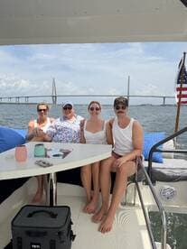 A cheerful group enjoys their time on a boat with a stunning bridge in the background, perfect for family gatherings or celebrations on the water.