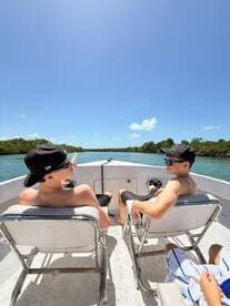Two friends relax on a boat, enjoying the scenic views of mangroves under a clear blue sky — a perfect day for adventure and exploration.