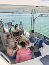 A lively group enjoys a meal and drinks aboard a boat, capturing the essence of a fun-filled day on the water with friends.