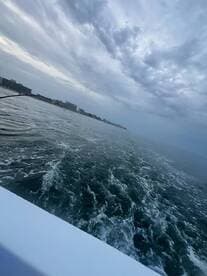 A serene view from a boat showing the wake and cloudy sky, perfect for capturing the essence of a peaceful day on the water.