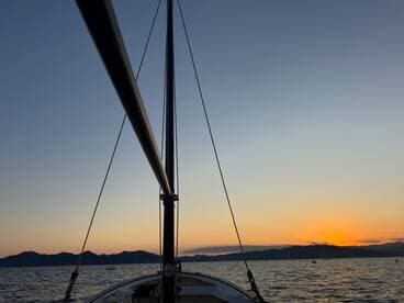 A stunning view of a sailboat's mast against a vibrant sunset, capturing the serene beauty of a sailing experience on calm waters.