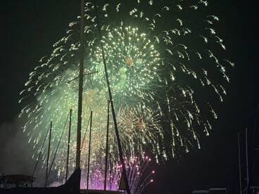 A stunning display of fireworks lights up the night sky, viewed from a boat, creating a festive atmosphere perfect for celebrations.