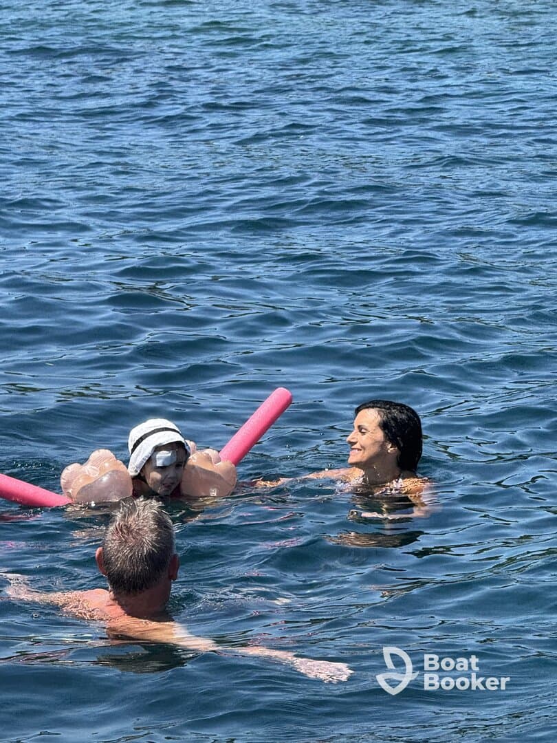 A joyful moment in the water as a child enjoys swimming with family, showcasing fun and relaxation during a sunny day on the water.