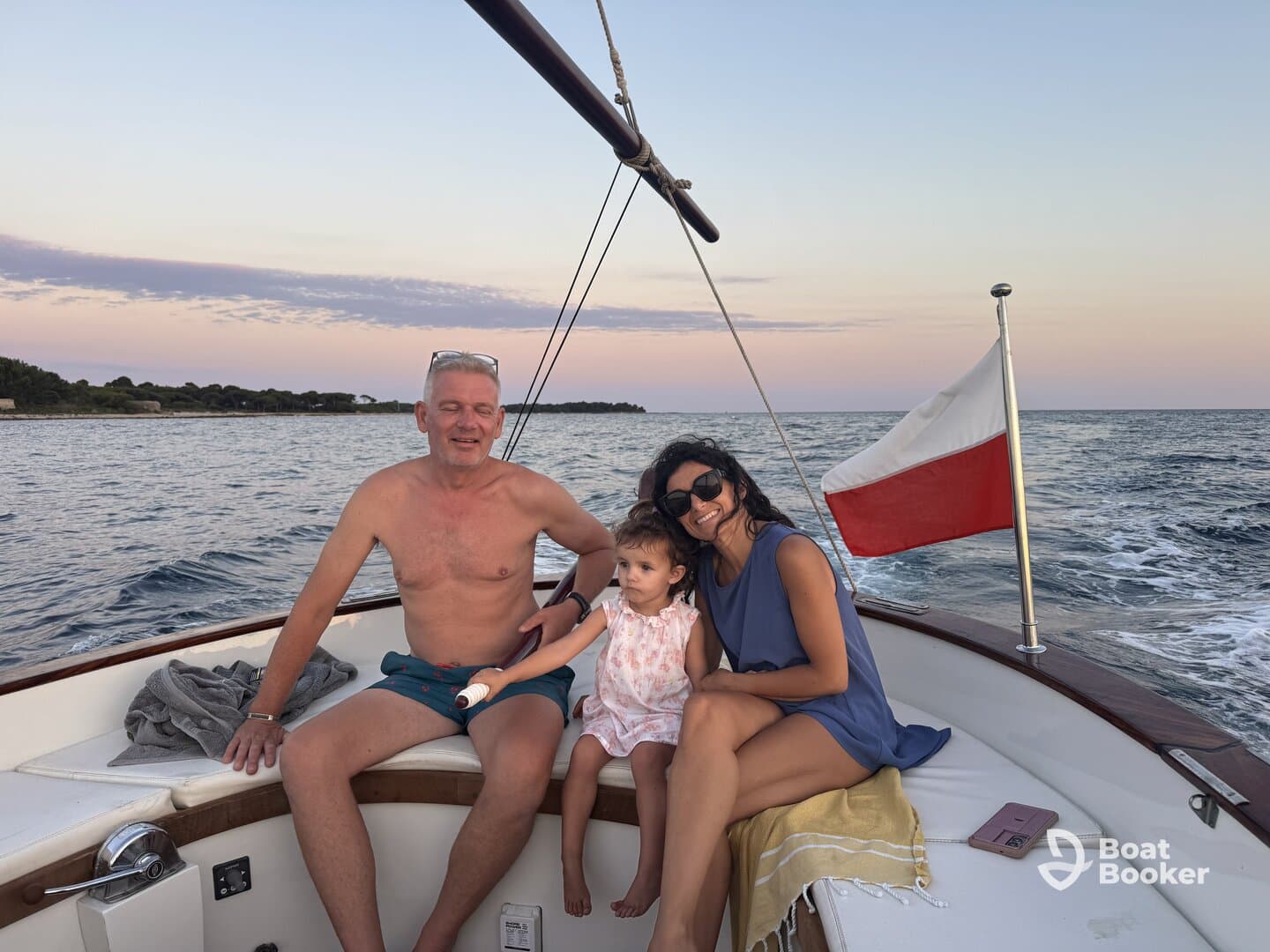 A joyful family enjoys a sunset cruise on a boat, capturing precious moments together with the serene waters as their backdrop.