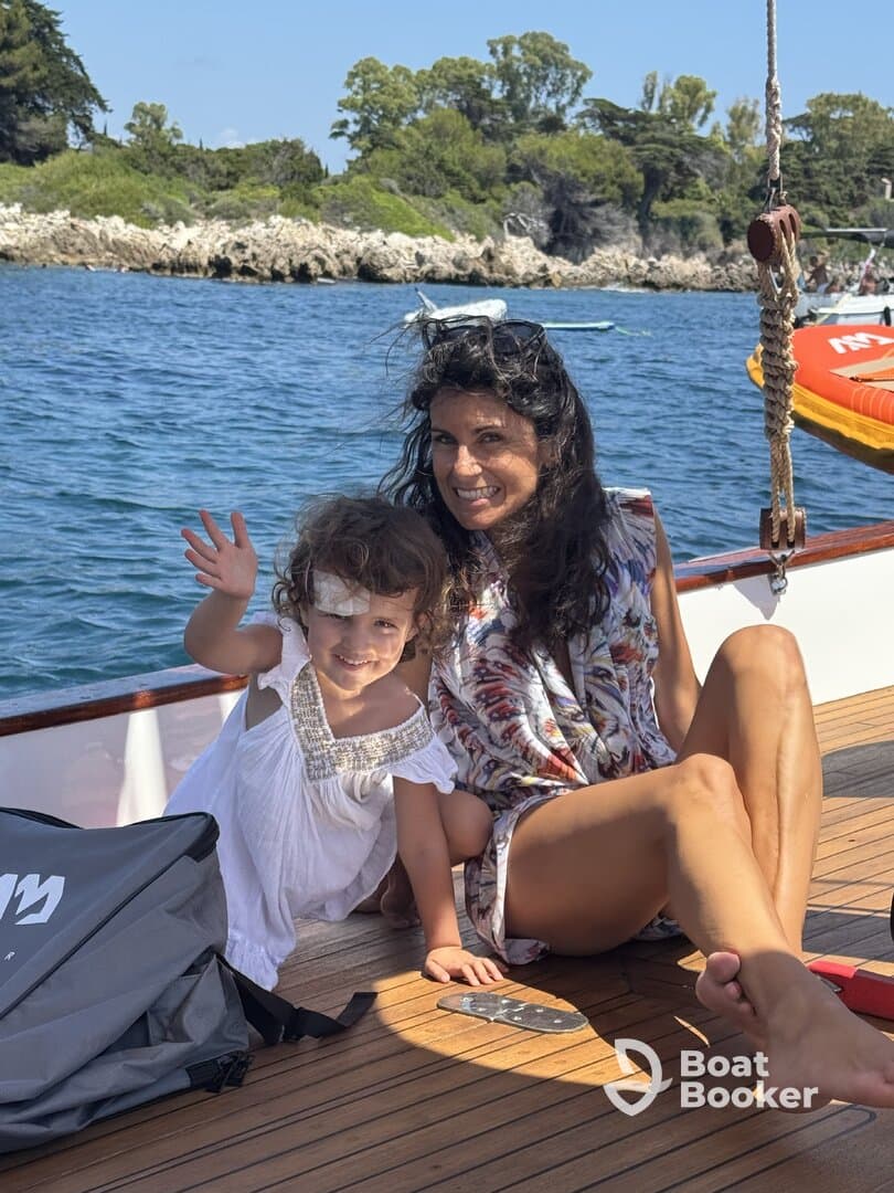 A joyful moment captured on a boat, featuring a mother and her young daughter enjoying their time together by the ocean, perfect for family outings and adventures.