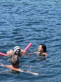 A joyful moment in the water as a child enjoys swimming with family, showcasing fun and relaxation during a sunny day on the water.