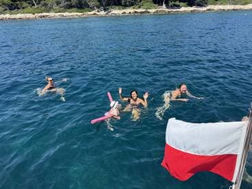 A lively group enjoys swimming in crystal-clear waters, showcasing the fun and excitement of a day on the boat.