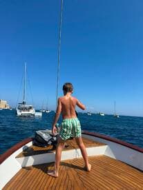 A young boy enjoys a sunny day on a boat, showcasing the joy of summer sailing on the open ocean.