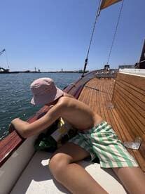 A young boy enjoys a sunny day on a boat, leaning over the side to explore the water — a perfect moment for family adventures on the sea.