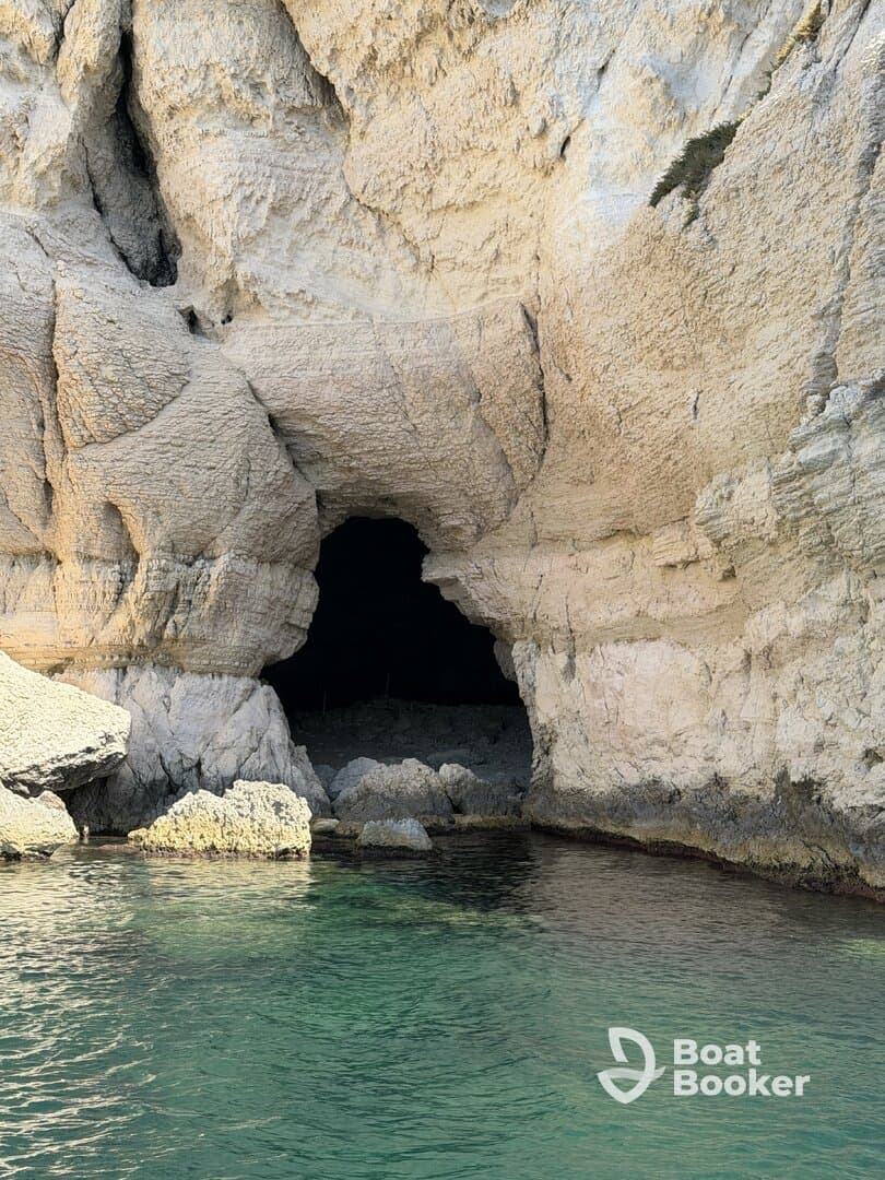 A stunning view of a natural cave along the coastline, showcasing the unique rock formations and clear turquoise waters — perfect for exploring hidden gems during a boating adventure.
