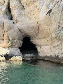 A stunning view of a natural cave along the coastline, showcasing the unique rock formations and clear turquoise waters — perfect for exploring hidden gems during a boating adventure.