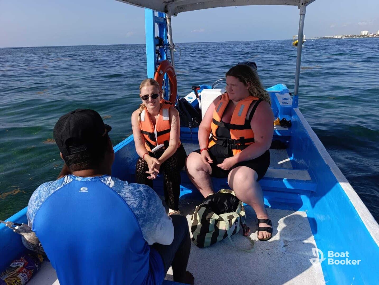 Two women wearing life jackets engage in conversation aboard a small boat, enjoying their time on the water — a perfect setting for memorable adventures.