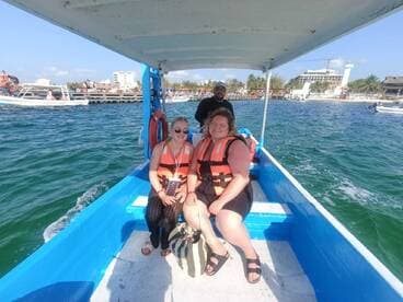 A cheerful group enjoys a boat ride, wearing life jackets and soaking in the sun — a perfect adventure on the water.
