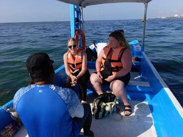 Two women wearing life jackets engage in conversation aboard a small boat, enjoying their time on the water — a perfect setting for memorable adventures.
