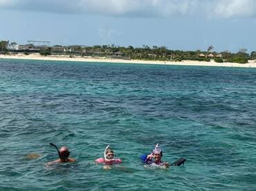 A family enjoys snorkeling in crystal-clear waters, surrounded by a beautiful beach backdrop — perfect for aquatic adventures and family bonding.