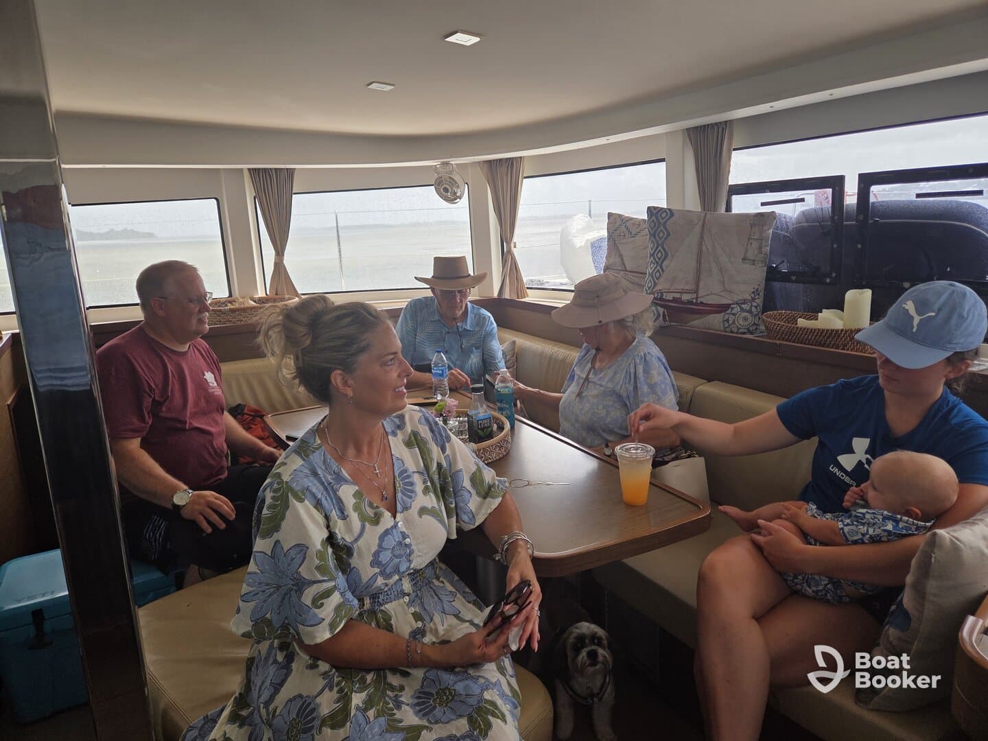 A cozy interior shot of a boat's cabin featuring a group of guests enjoying their time together, with a baby and a dog present, perfect for family outings on the water.