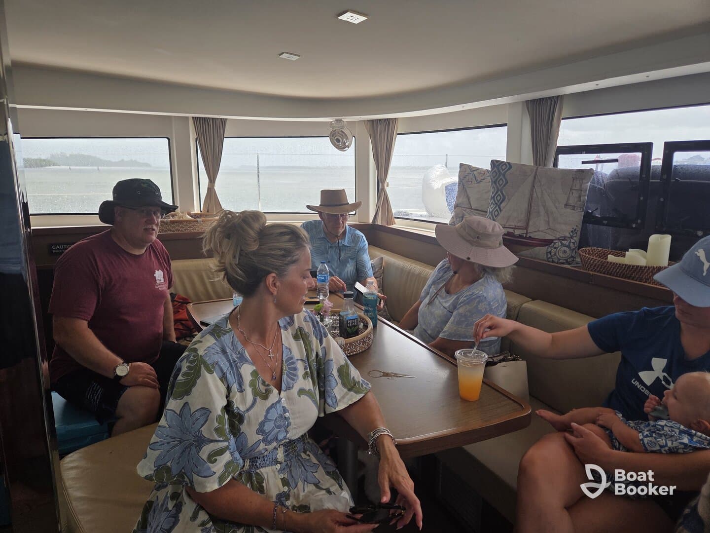 A cozy interior shot of a boat's cabin featuring a group of guests enjoying drinks and conversation, perfect for relaxing during a boating trip.