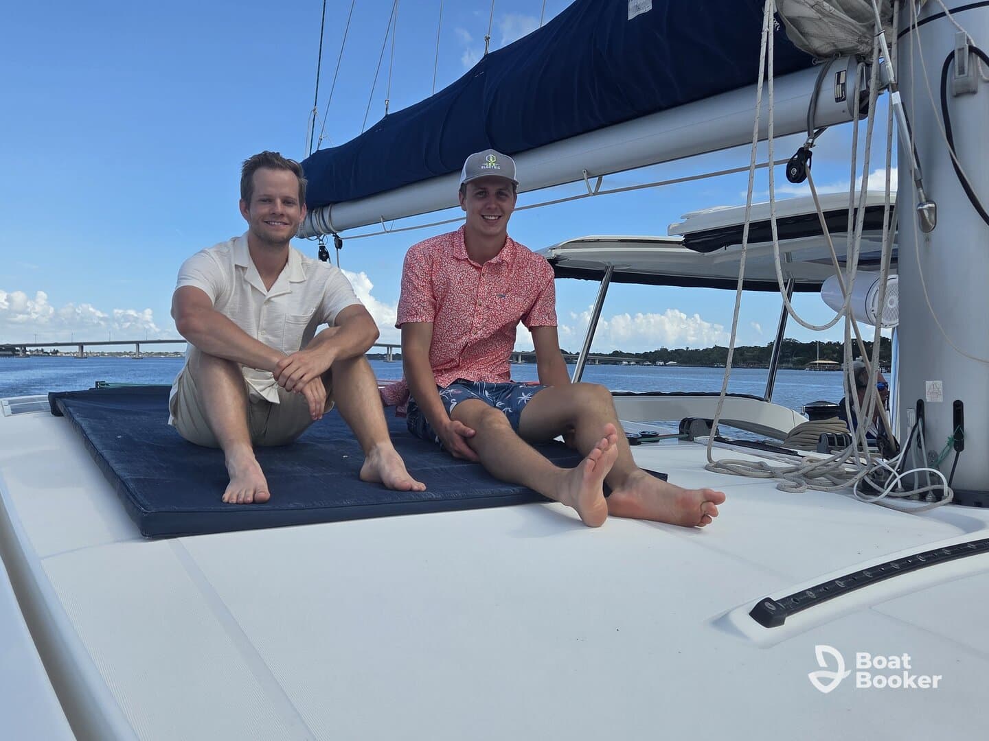 Two friends relax on the deck of a catamaran, enjoying a sunny day on the water — perfect for social outings and leisure adventures.