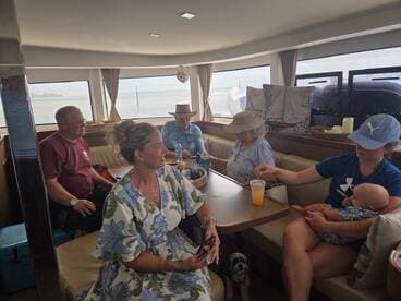 A cozy interior shot of a boat's cabin featuring a group of guests enjoying their time together, with a baby and a dog present, perfect for family outings on the water.