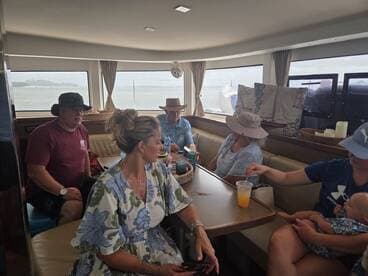 A cozy interior shot of a boat's cabin featuring a group of guests enjoying drinks and conversation, perfect for relaxing during a boating trip.