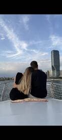 A couple enjoys a romantic moment on the deck of a boat, overlooking a stunning city skyline — perfect for intimate outings or sunset cruises.
