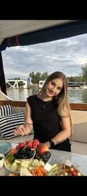 A young woman enjoys a colorful fruit platter on a boat, perfect for a relaxing day on the water with delicious snacks.