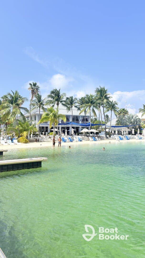 A scenic view of a beach resort with guests enjoying the clear waters and palm trees, perfect for a relaxing getaway.