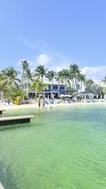 A scenic view of a beach resort with guests enjoying the clear waters and palm trees, perfect for a relaxing getaway.