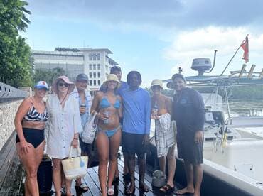 A cheerful group poses together on the dock next to their boat, ready for a fun day on the water. Perfect for family gatherings or friends' outings.